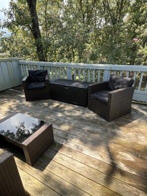 An outdoor deck with a seating area consisting of a sofa and chairs, a glass-top table, and a white railing. - Fairfield Harbour Condo, Sleeps 6, Close to Golf, Marina, and Downtown New Bern. (New Bern)