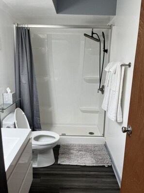 Een kleine badkamer met toilet, douchecabine en wastafel.