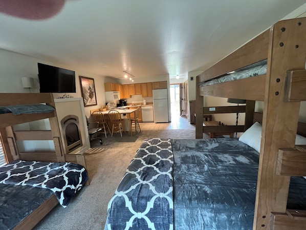 A compact room with bunk beds, a kitchenette, and a dining area.