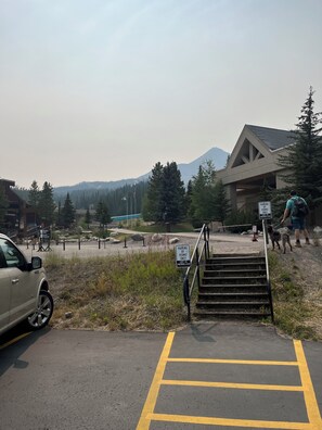 A parking area with a permit-only sign, a car, and a building with a mountain in the background.