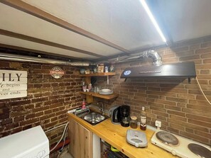 A compact kitchen with a brick wall, a coffeehouse sign, and a modern coffee machine. - Cozy Kerkyra Studio with Extra Beds (Kerkira)