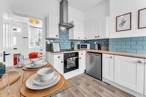 Eine moderne Küche mit weißen Schränken, einer blauen Fliesenspiegel und einer Holz Arbeitsplatte.