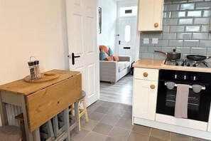 Una cocina compacta con estufa, horno y una pequeña mesa de madera con una cesta.