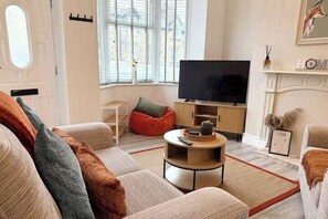 Una sala de estar con un sofá, una mesa de centro, un televisor y una chimenea.