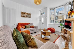 A modern living room with a sofa, a coffee table, and a TV displaying the Netflix logo. - 3Bedroom Sleeps 5 at Buxton (Buxton)