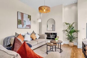 A living room with a sofa, a coffee table, a TV, and a plant. - 2 Bedroom House at Buxton Peak District (Buxton)