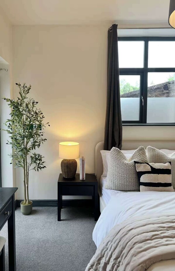 A bedroom with a bed, bedside table, lamp, and a potted plant. - New Cosy Retreat in Matlock Bath (Matlock Bath)