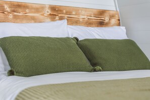 Ein Bett mit weißer Bettwäsche und zwei grünen Kissen.