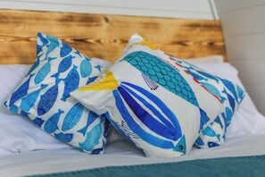 Ein Bett mit zwei Kissen, verziert mit einem Fischmuster.