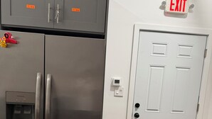 Un frigorifero in acciaio inossidabile con vano congelatore, una porta bianca con maniglia e un segnale di uscita sopra.