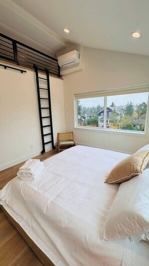 A bedroom with a large bed, a window with a view, a ladder, and an air conditioning unit. - Premium 3BR Suite Minutes to Downtown (Seattle)