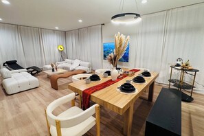 A modern living room with a dining area, a sofa set, a massage chair, and a TV. - Premium 3BR Suite Minutes to Downtown (Seattle)