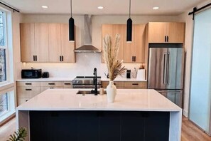 A modern kitchen with a central island, stainless steel appliances, and pendant lighting. - Premium 3BR Suite Minutes to Downtown (Seattle)