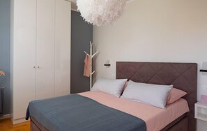 Ein Schlafzimmer mit einem Bett, einem Kleiderschrank, einem Kleiderhaken und einer Wandleuchte.