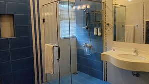 Une salle de bain avec une douche à parois de verre, un lavabo avec un miroir et des murs recouverts de carreaux bleus.