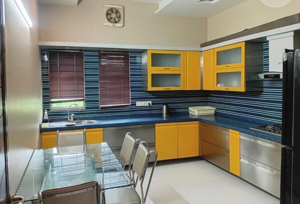 A modern kitchen with yellow cabinets, a blue countertop, and a dining area with a glass table and chairs.