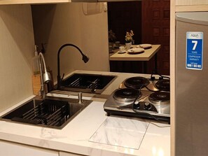 Une cuisine de taille réduite, équipée d’un évier à deux bacs, d’une cuisinière et d’un réfrigérateur.