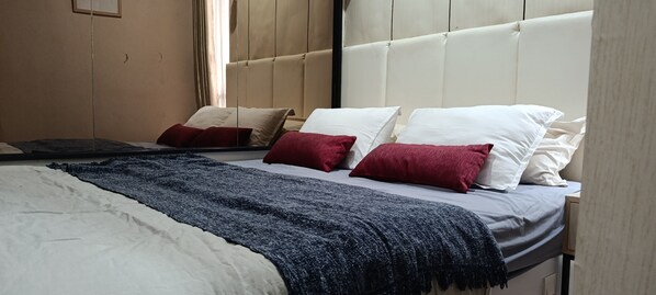 A bed with a headboard, white and red pillows, a dark blue throw blanket, and a wooden headboard. - Guesthouse Puri at Kemang (Jakarta Selatan)