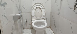 A toilet with a manual flush handle and a wall-mounted bidet. - Guesthouse Puri at Kemang (Jakarta Selatan)
