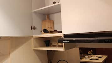 A kitchen with white cabinets, a black range hood, and a small table with dishes.