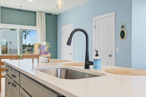 Une cuisine moderne avec un évier en acier inoxydable, un robinet noir et un flacon de savon liquide posé sur le comptoir.