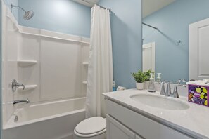 A bathroom with a bathtub, toilet, sink, and a shower with a curtain. - Cane Bay / Summerville getaway—where Southern hospitality meets modern comfort. (Summerville)