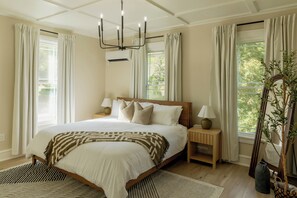 Una camera da letto con un letto grande, due comodini, un lampadario e vista sul verde.