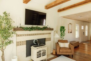 Ein Wohnzimmer mit Kamin, einem darüber montierten Fernseher und einem Sofa.