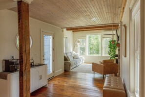 A spacious living area with a wooden floor, a sofa, a bench, and a coffee station.