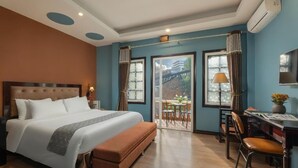 A hotel room with a large bed, a desk, and a balcony with a view. - Sapa Fansipan View House (Sa Pa)