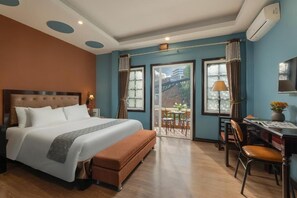 A hotel room with a large bed, a desk, and a balcony with a view. - Sapa Fansipan View House (Sa Pa)