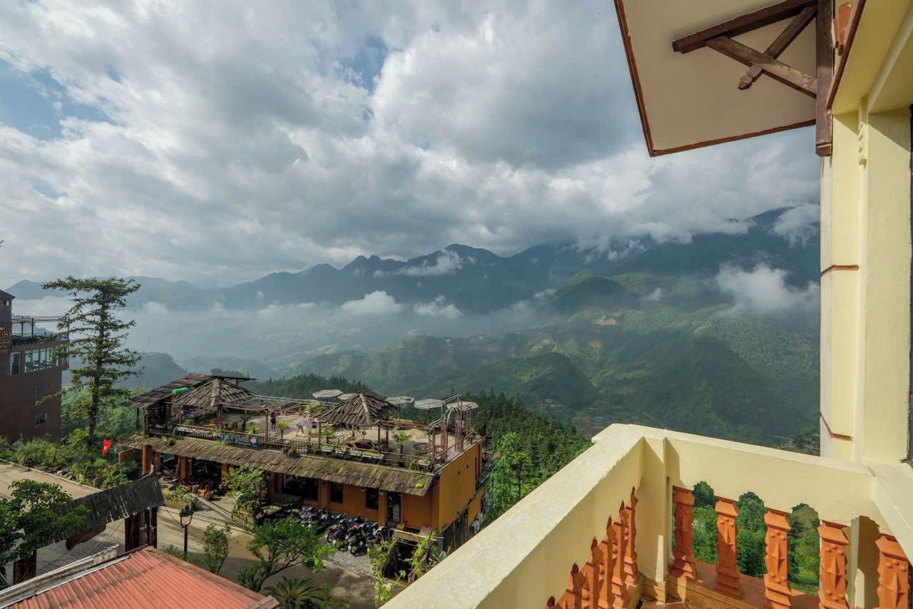 A mountainous landscape with a building featuring a balcony and a view of the surrounding hills.