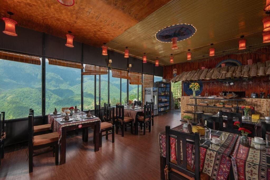 A restaurant with wooden floors, tables, and chairs, large windows with a mountain view, and hanging lanterns.
