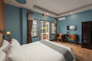 Una habitación de hotel con una cama, un escritorio, una silla, un televisor y vistas al exterior.