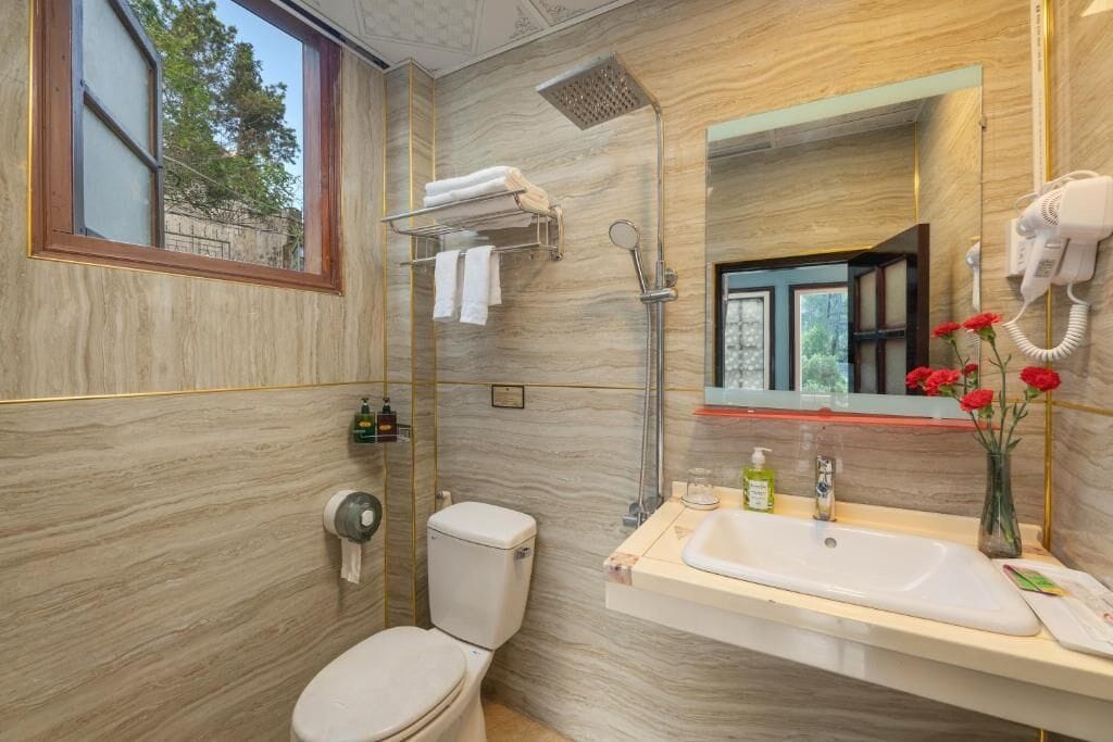 Un baño con inodoro, lavamanos, ducha y espejo.