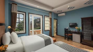 A hotel room with two beds, a desk, a television, and a view of the outdoors.