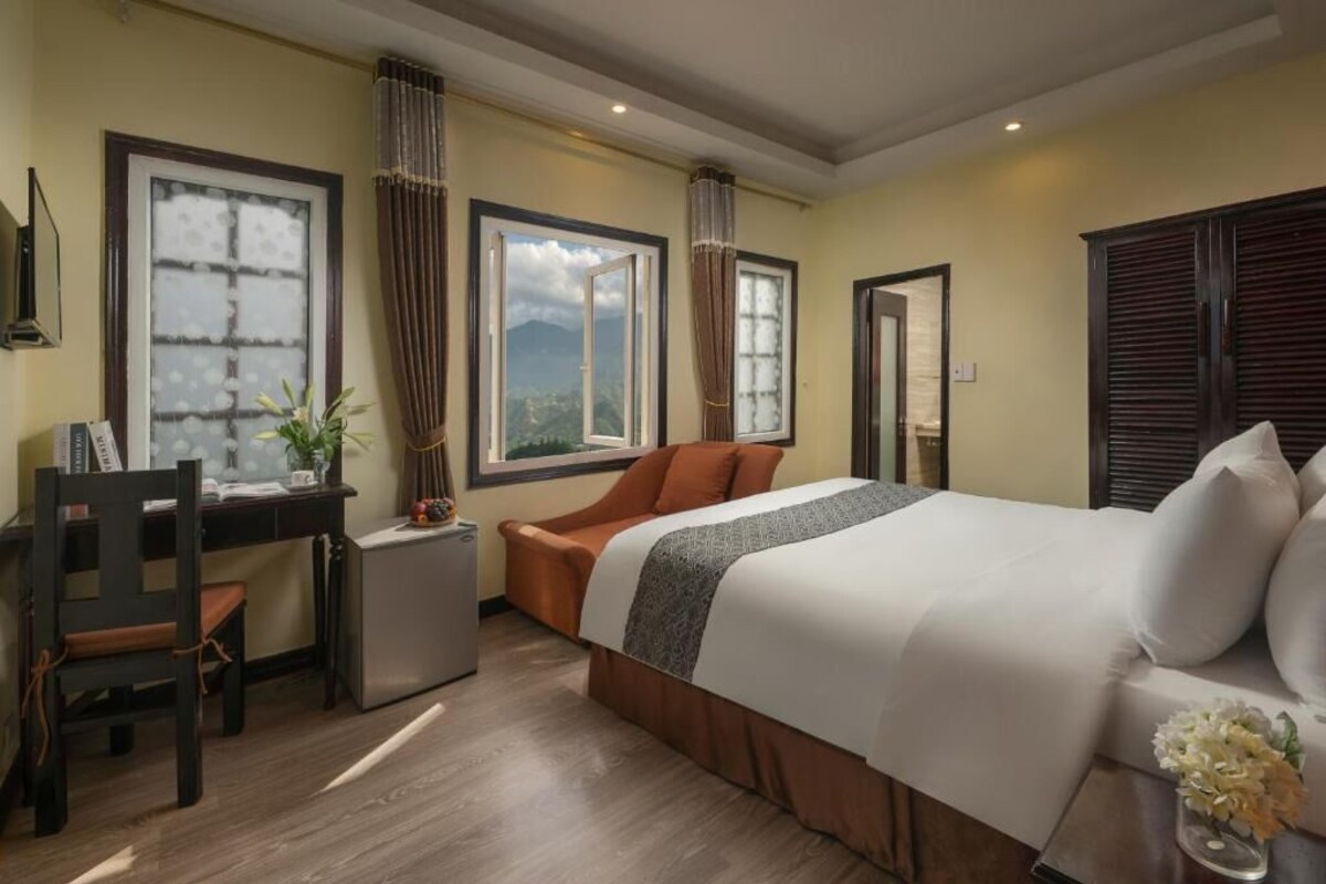 A hotel room with a bed, a desk, a chair, and a view of the outdoors.