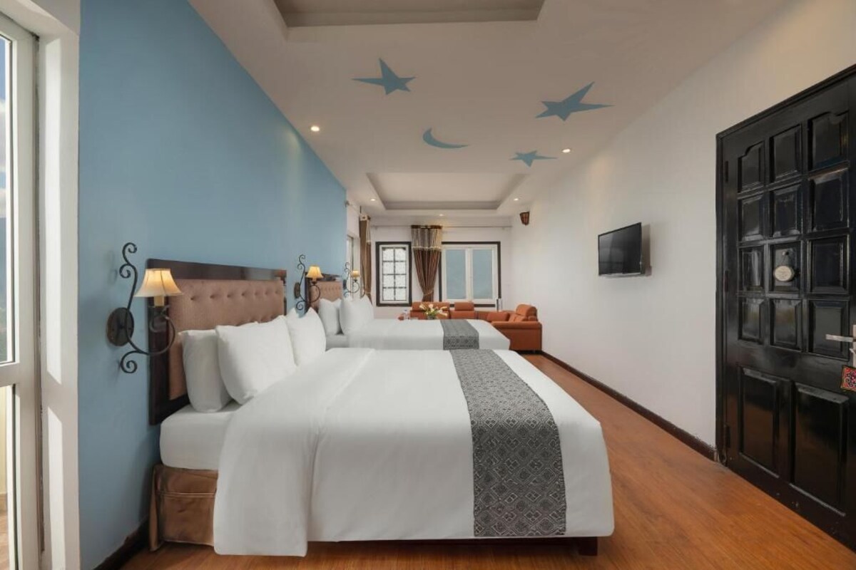 A hotel room with two beds, a TV, a door, and a window.