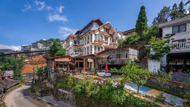 A multi-story building with balconies, a street in front, and a small garden area. - Sapa Fansipan View House (Sa Pa)
