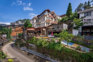 A multi-story building with balconies, a street in front, and a small garden area. - Sapa Fansipan View House (Sa Pa)