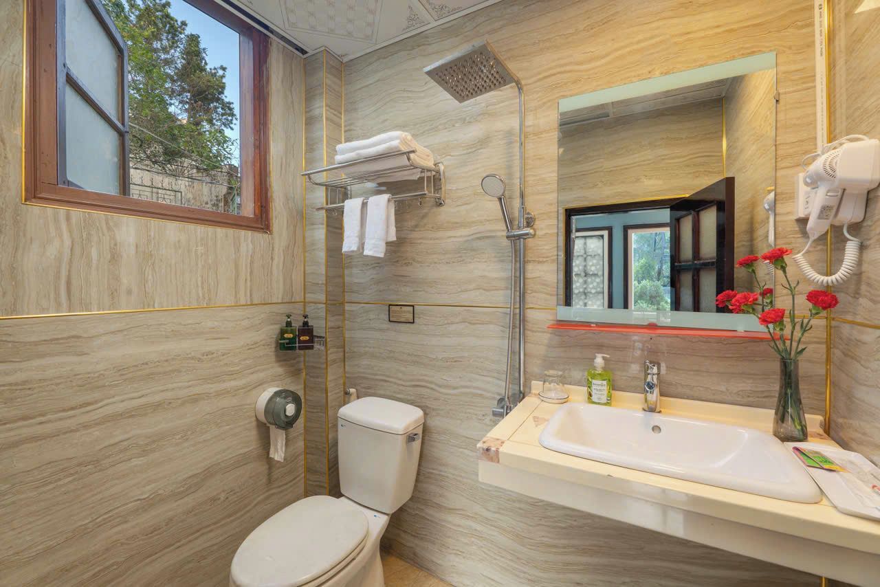 Un baño con inodoro, ducha, lavamanos y espejo.