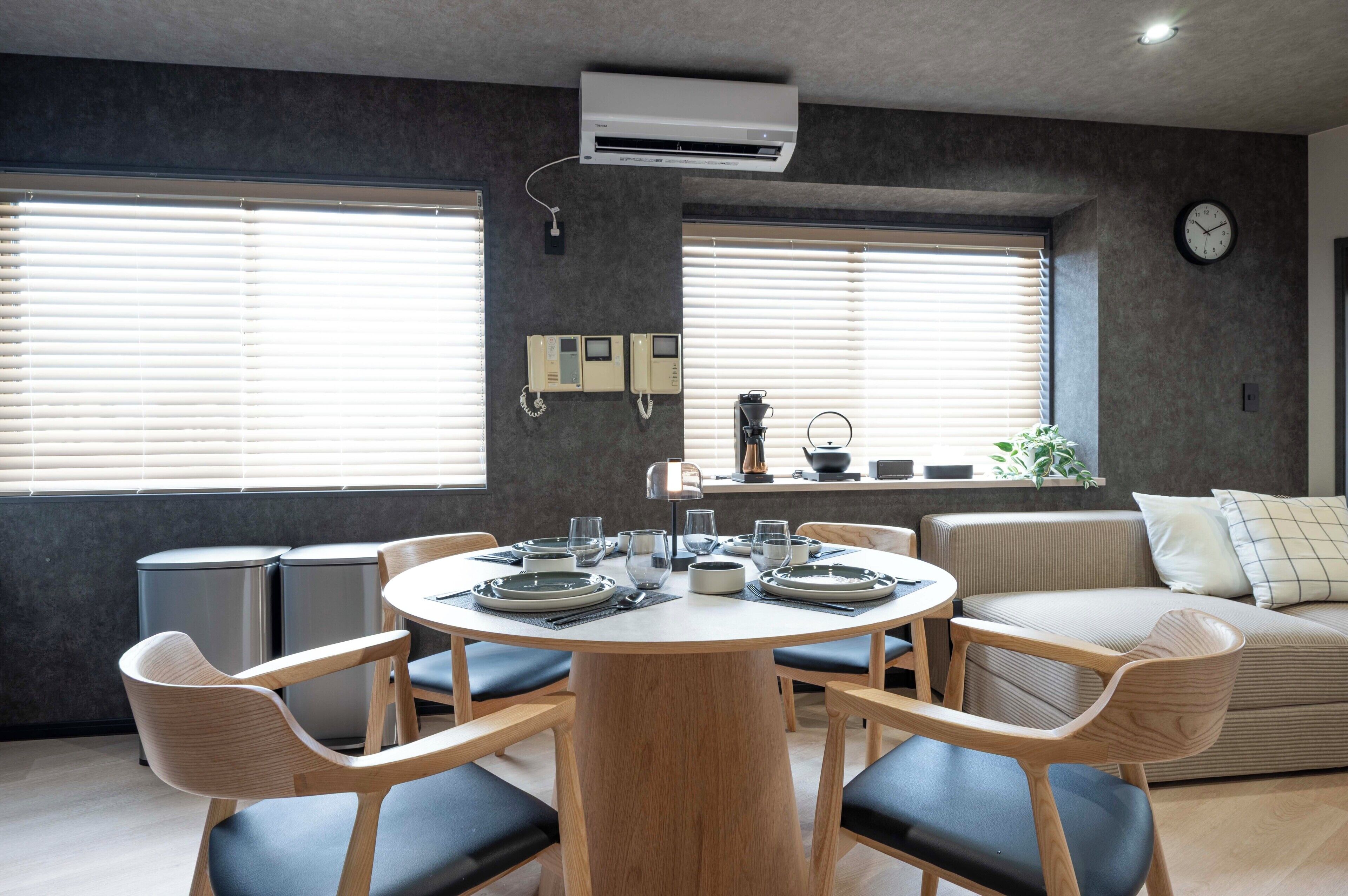 A modern dining area with a round table, chairs, and a built-in coffee machine.
