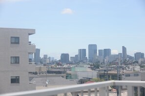Une vue sur les toits d’une ville, avec des bâtiments modernes, un ciel dégagé et, au premier plan, un quartier résidentiel avec un immeuble à toit plat.