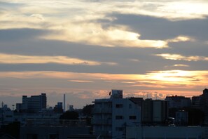Ein Stadtbild bei Sonnenuntergang, Gebäude zeichnen sich als Silhouetten gegen den Himmel ab.