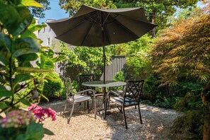 A patio with a table and chairs, surrounded by a wooden fence and lush greenery. - Georgetown’s Secret Garden in the West Village, Steps from the University (Washington)