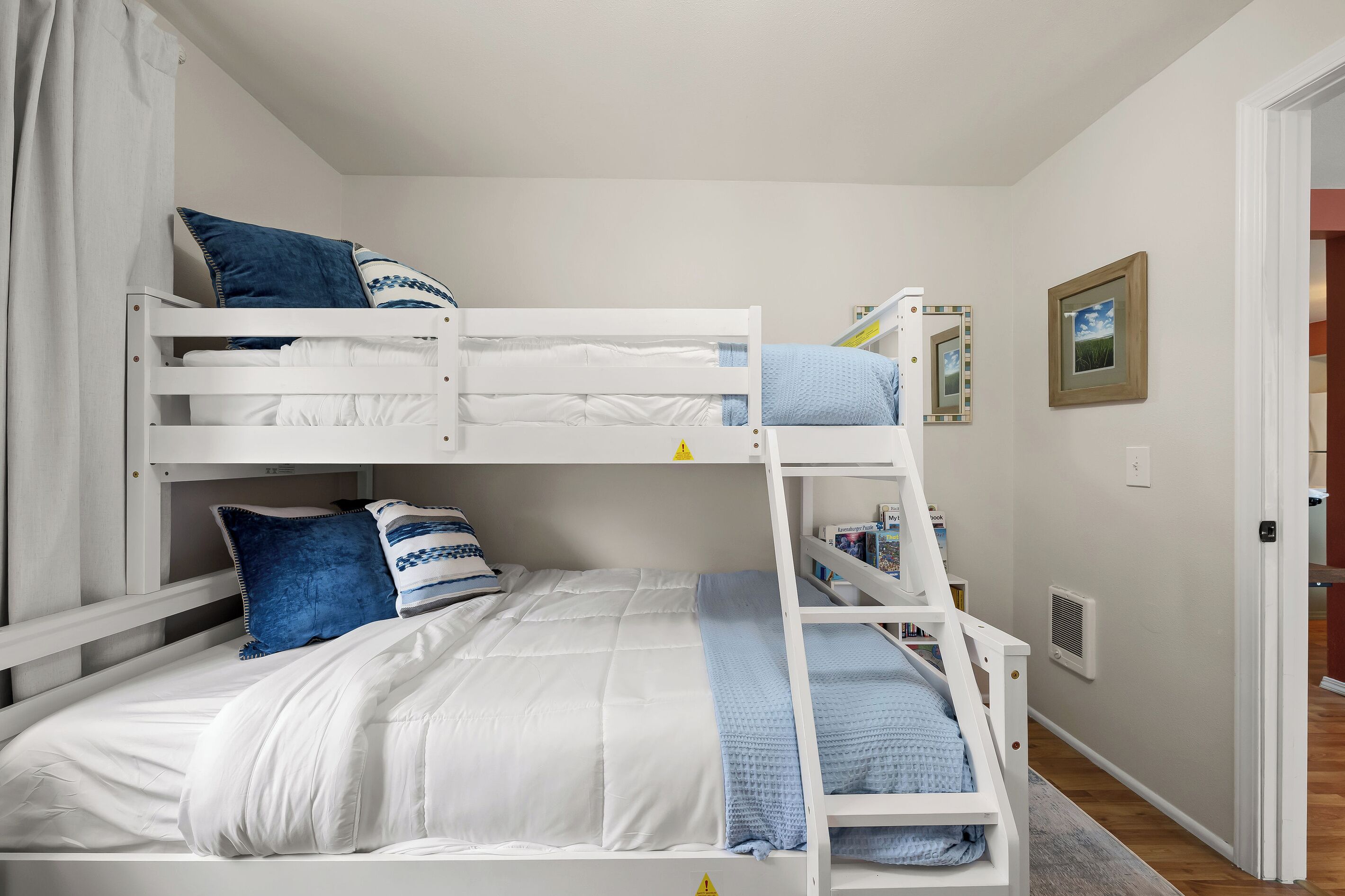 A bunk bed with a ladder, white bedding, and blue pillows.