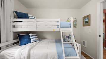 A bunk bed with a ladder, white bedding, and blue pillows.
