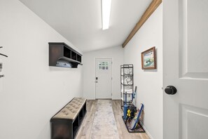 Un pasillo con un banco, perchero, puerta y un cuadro en la pared.