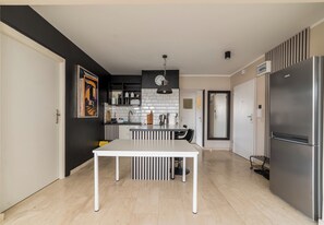 Eine moderne Küche mit Esstisch, Kühlschrank und einer Uhr an der Wand.