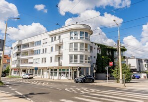 Un edificio a più piani con facciata bianca, ampie finestre e un ingresso angolare.